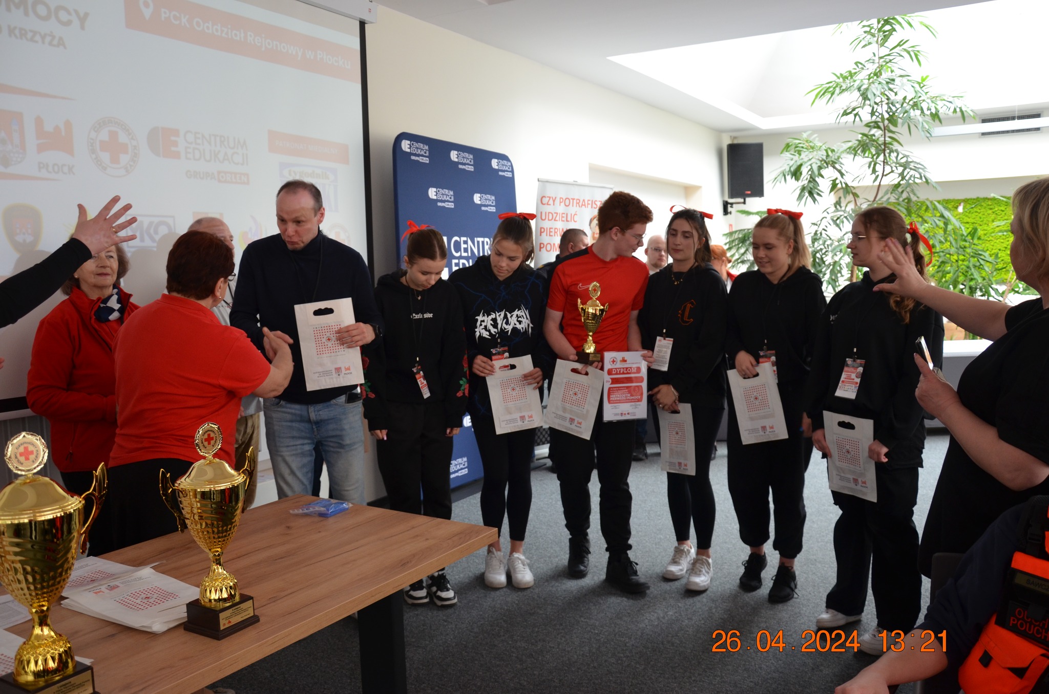 Laureaci etapu rejonowego XXX Ogólnopolskich Mistrzostw Pierwszej Pomocy PCK w Płocku stoją w sali podczas wręczenia dyplomów i pucharów.