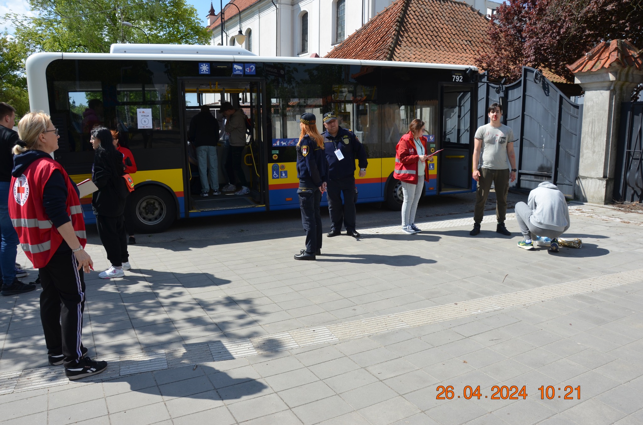 Uczestnicy i sędziowie etapu rejonowego XXX Ogólnopolskich Mistrzostw Pierwszej Pomocy PCK w Płocku przeprowadzają pozorowaną akcję przy miejskim autobusie.