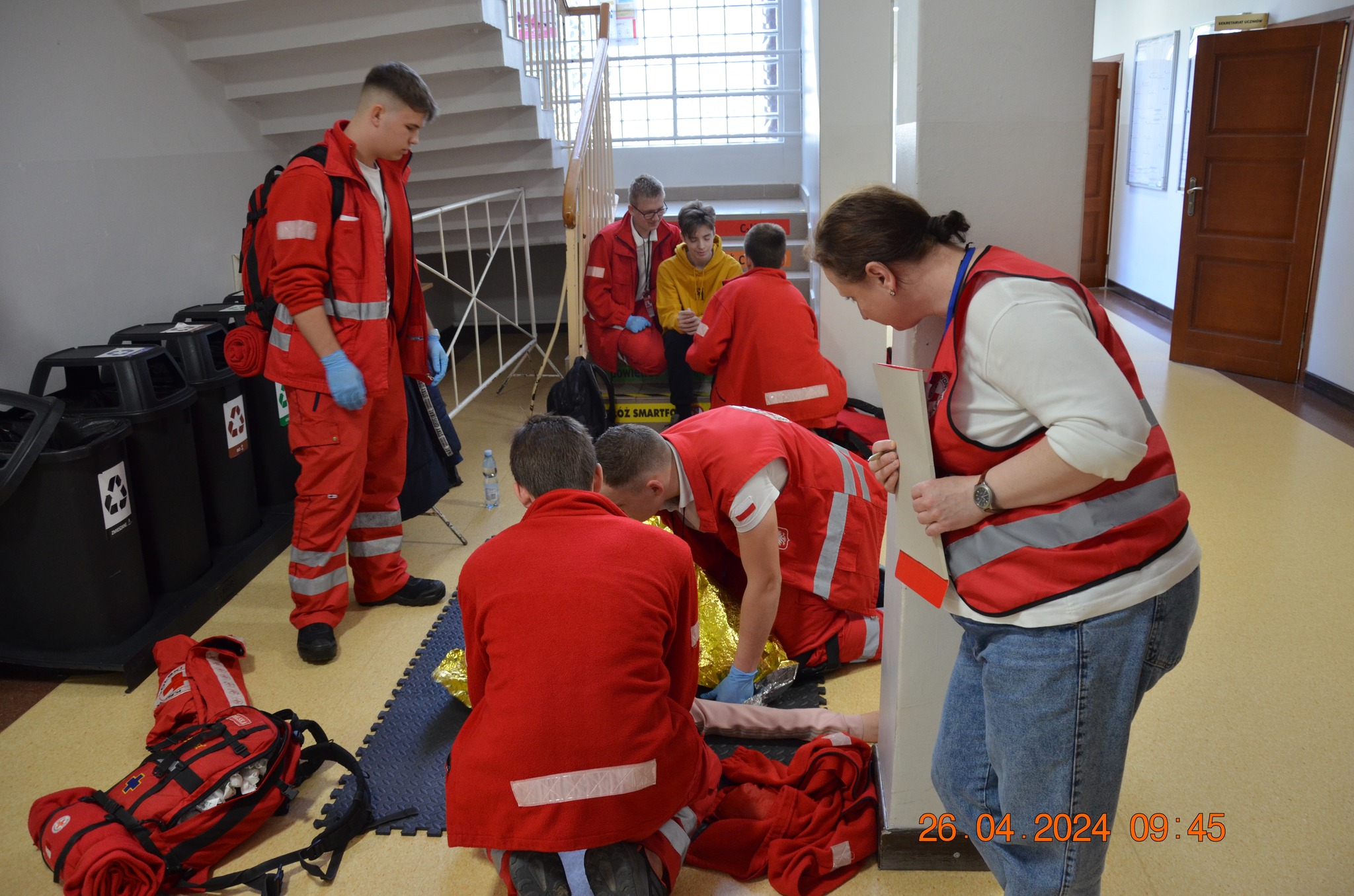 Zawodnicy Polskiego Czerwonego Krzyża w czerwonych strojach ćwiczą udzielanie pierwszej pomocy podczas etapu rejonowego XXX Ogólnopolskich Mistrzostw Pierwszej Pomocy w Płocku.
