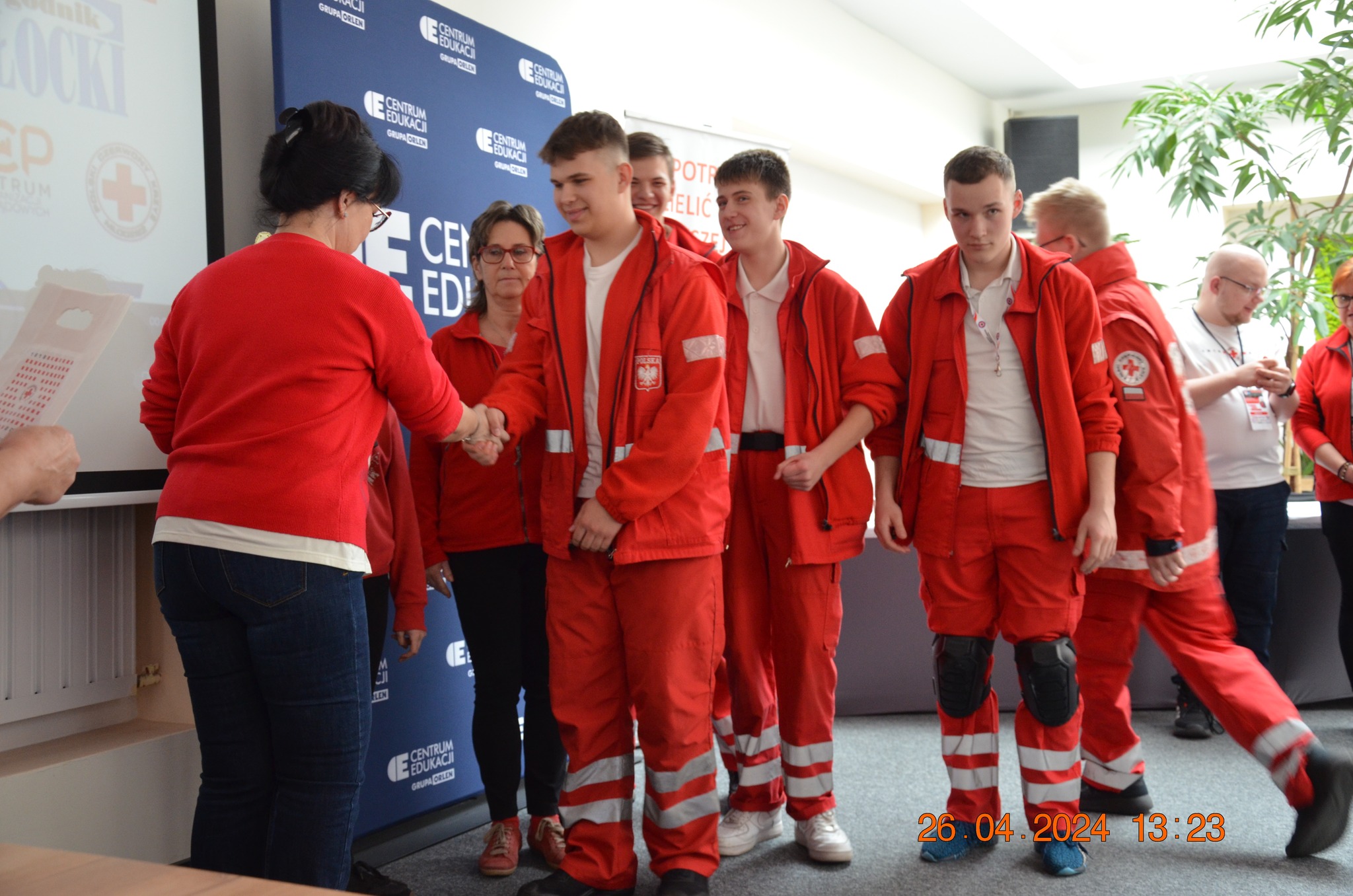 Uczestnicy w czerwonych strojach ratowniczych odbierają gratulacje podczas etapu rejonowego XXX Ogólnopolskich Mistrzostw Pierwszej Pomocy PCK w Płocku.
