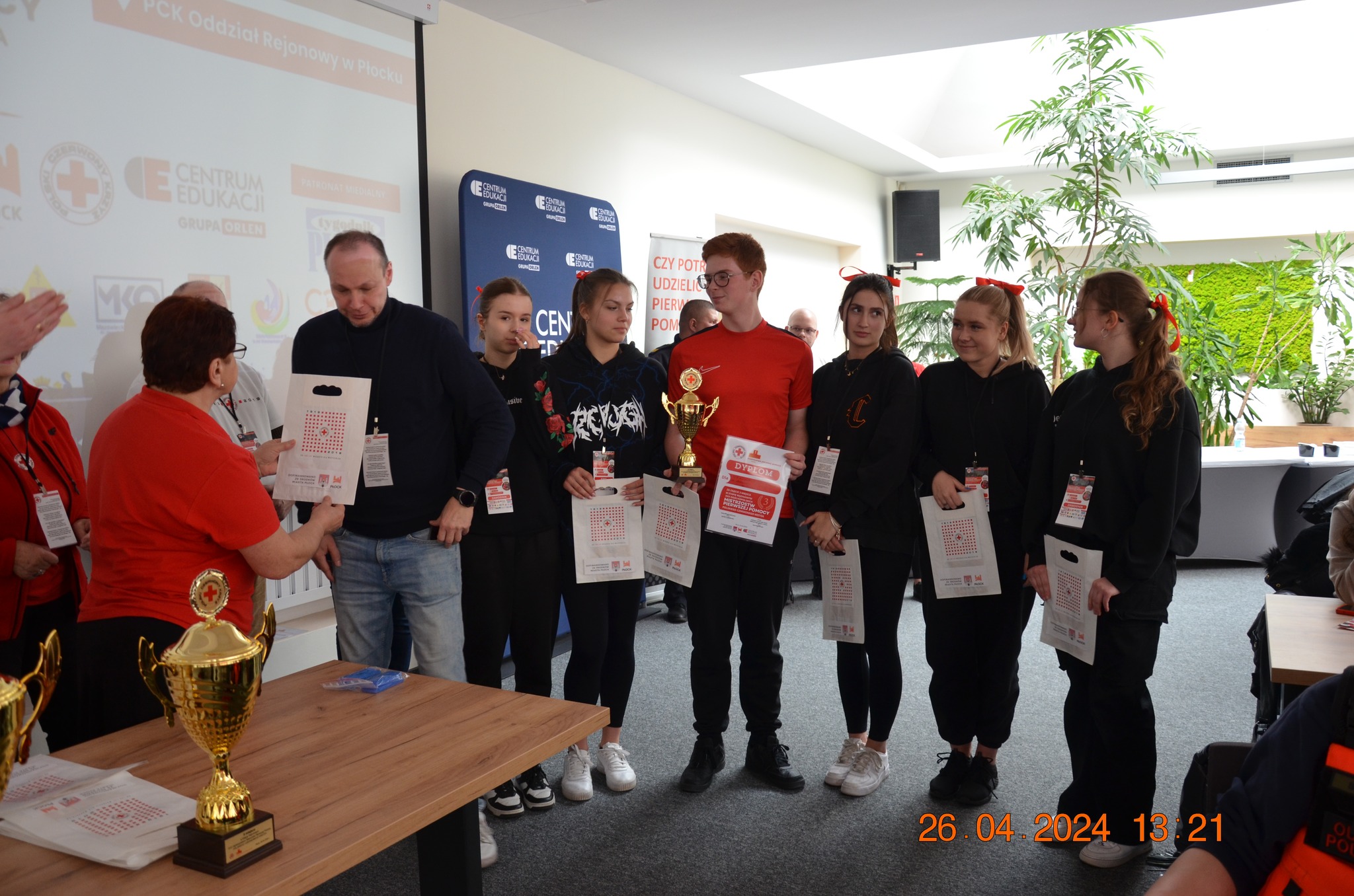 Grupa młodzieży odbiera dyplomy i puchar podczas ceremonii wręczenia nagród etapu rejonowego XXX Ogólnopolskich Mistrzostw Pierwszej Pomocy PCK w Płocku.