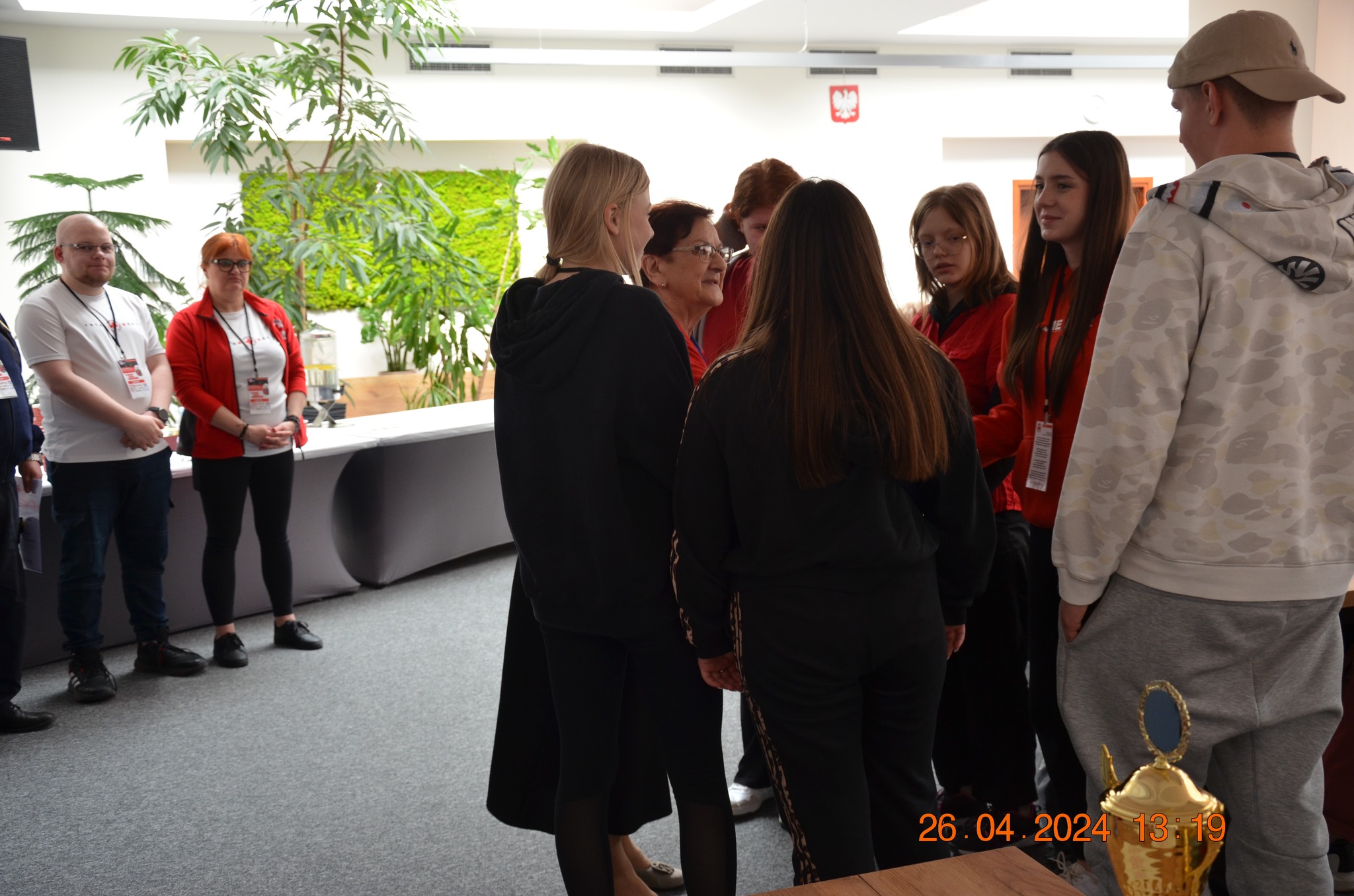 Grupa uczestników i organizatorów etapu rejonowego XXX Ogólnopolskich Mistrzostw Pierwszej Pomocy PCK w Płocku stoi w sali obrad podczas rozmowy.