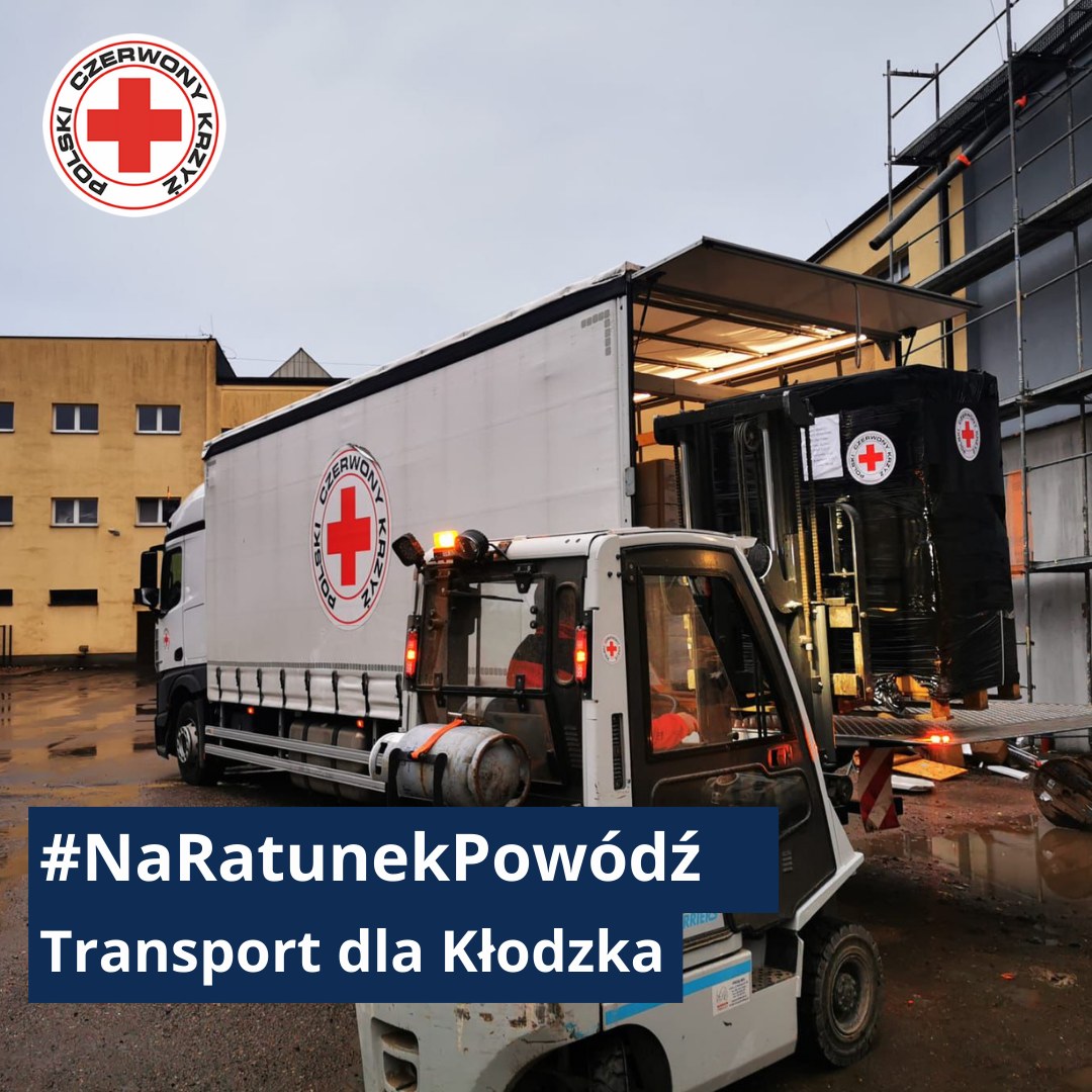 Wózek widłowy ładuje na ciężarówkę Polskiego Czerwonego Krzyża palety z pomocą humanitarną w ramach akcji „Na Ratunek – Powódź, transport dla Kłodzka”.