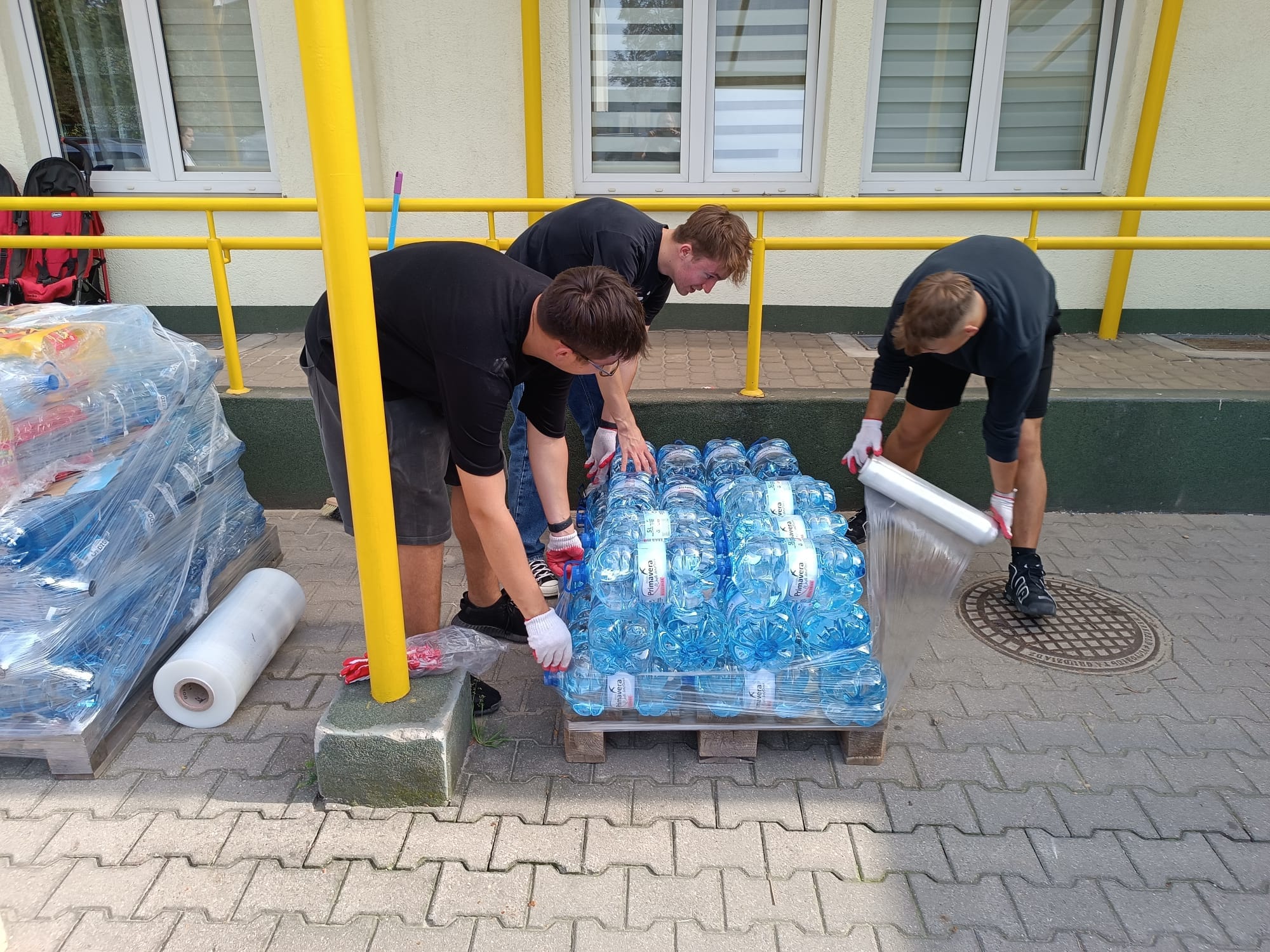 Wolontariusze Polskiego Czerwonego Krzyża pakują na palecie zgrzewki wody butelkowanej jako pomoc dla poszkodowanych.