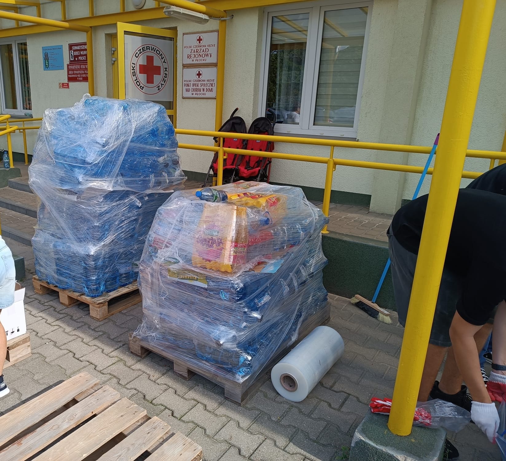 Palety z wodą i żywnością przed siedzibą Polskiego Czerwonego Krzyża, przygotowywane jako pomoc dla poszkodowanych.