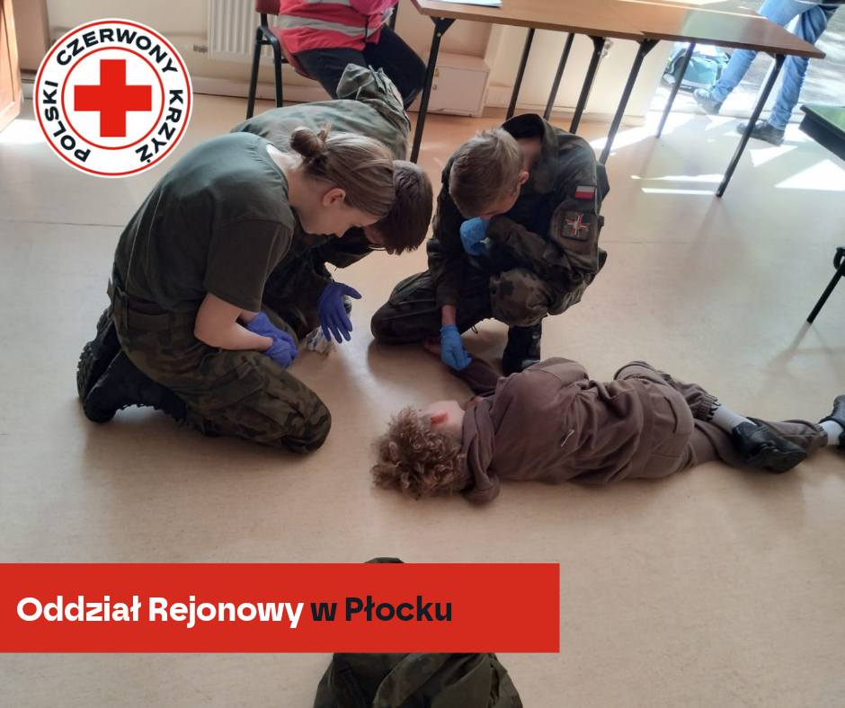 Uczestnicy XXXII Mistrzostw Pierwszej Pomocy PCK w Płocku ćwiczą udzielanie pomocy osobie pozorującej poszkodowanego leżącego na podłodze.