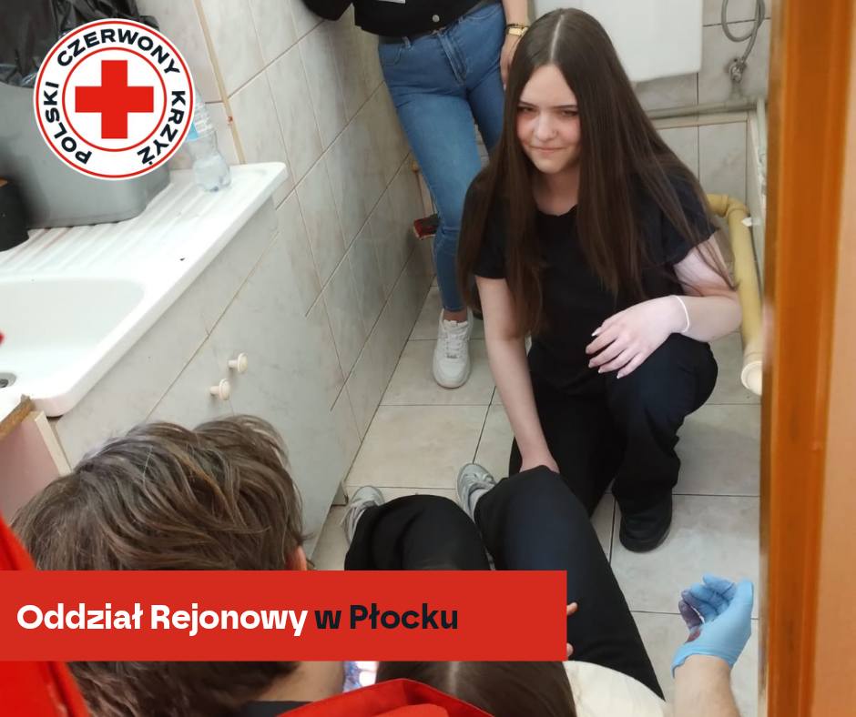 Młodzi wolontariusze Polskiego Czerwonego Krzyża udzielają pierwszej pomocy pozorowanemu poszkodowanemu w wąskiej łazience podczas XXXII Mistrzostw Pierwszej Pomocy PCK – etap rejonowy w Płocku 2026.