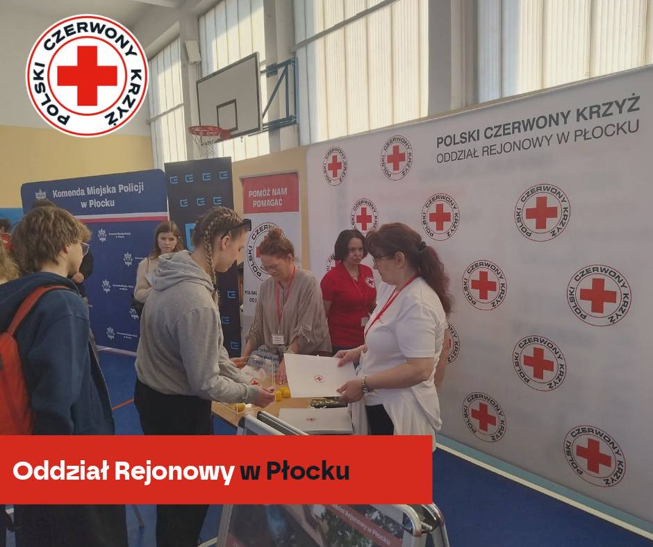 Uczestnicy XXXII Mistrzostw Pierwszej Pomocy PCK w Płocku odbierają materiały przy stoisku Oddziału Rejonowego Polskiego Czerwonego Krzyża na hali sportowej.