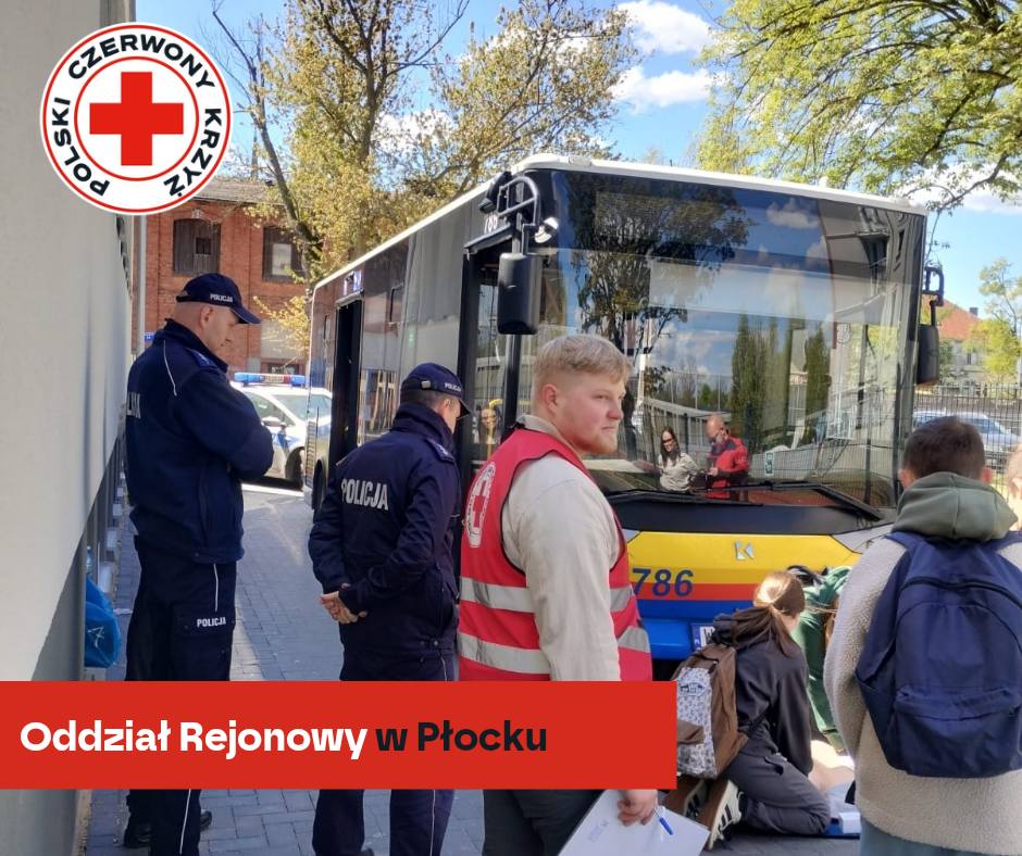 Wolontariusze PCK wraz z policjantami przeprowadzają symulację udzielania pierwszej pomocy przy autobusie podczas XXXII Mistrzostw Pierwszej Pomocy PCK w Płocku.